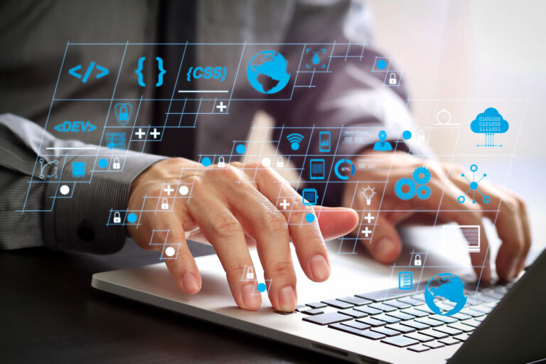 small business technology team member coding on a computer with augmented icons floating above keyboard